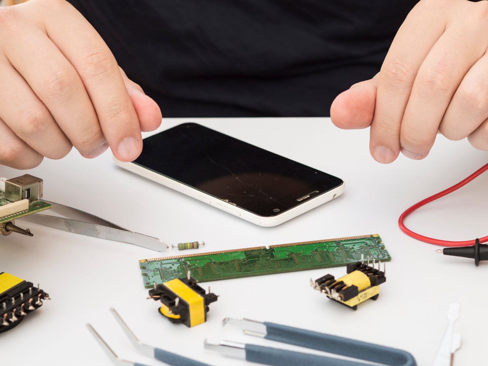 man sitting at a work station with electronics to repair