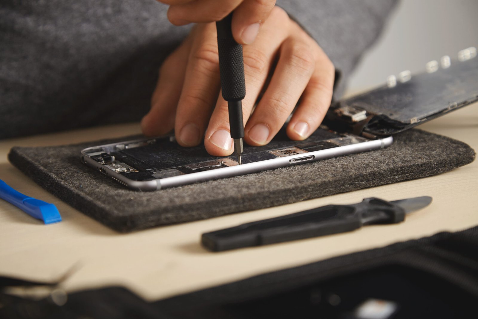 man using screw driver to remove screws from cell phone