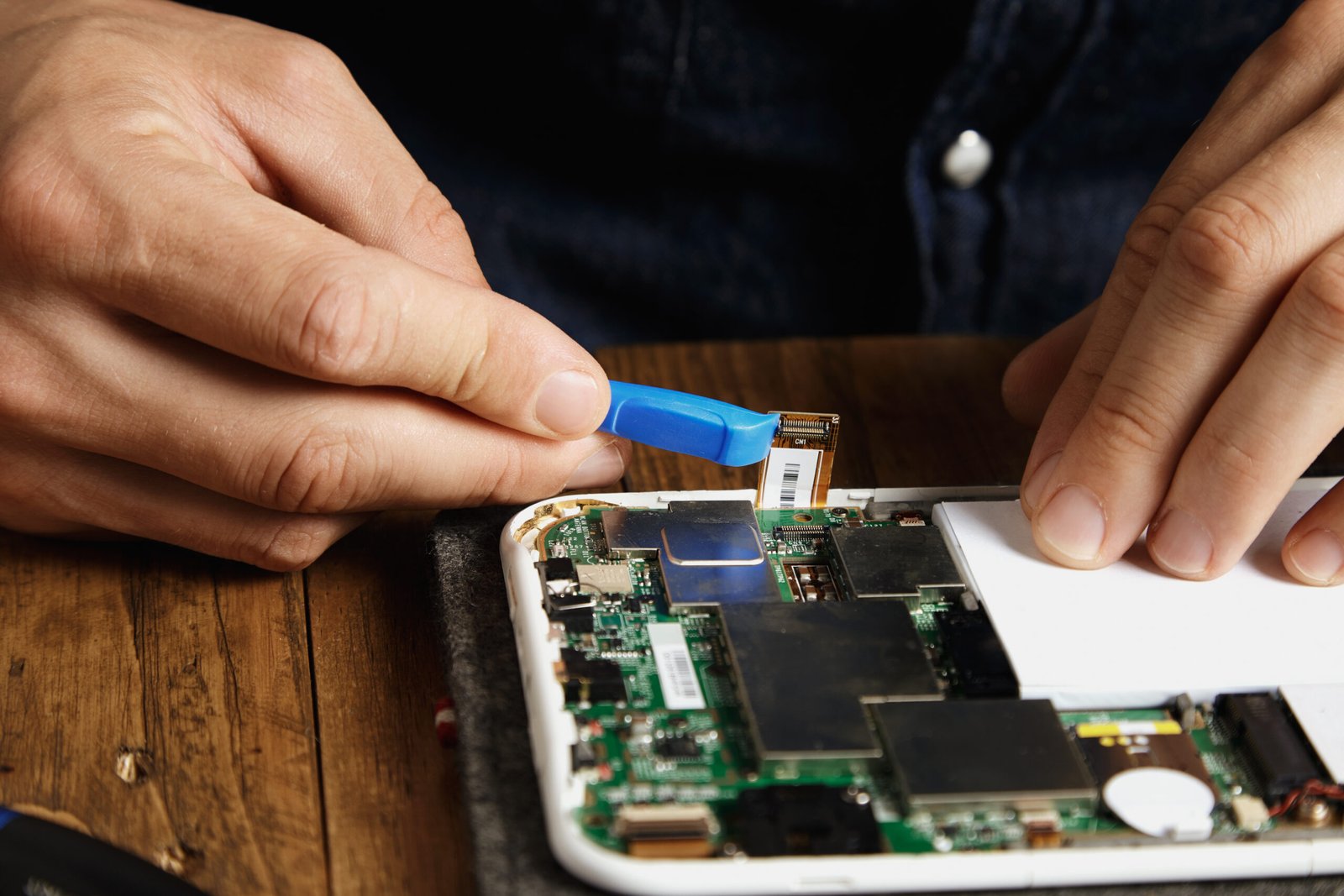 technician used special plastic tool to unclip electronic connector from a motherboard of a cell phone